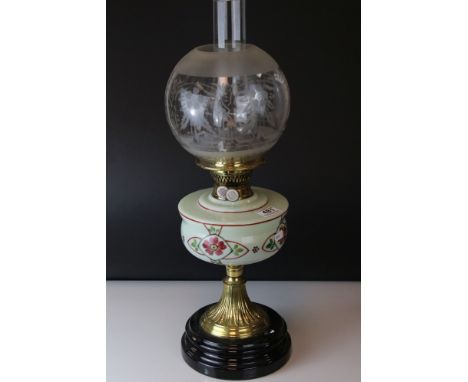 An early 20th century oil lamp with floral painted well glass globe and chimney