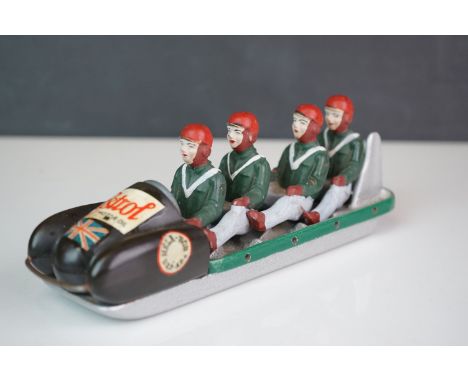 A vintage German cast metal model of a four man bobsled team.