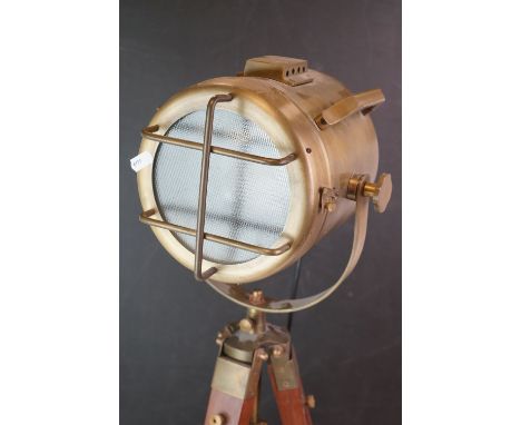 A contemporary brass spotlight on wooden tripod legs. 