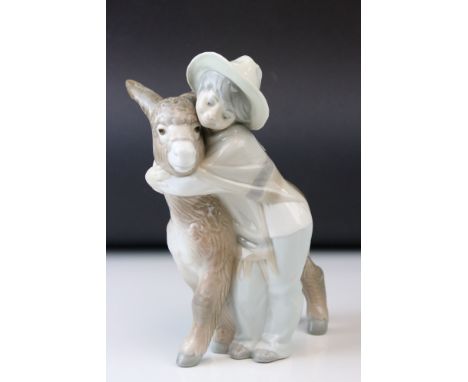 A Lladro figure of a Young boy cuddling a donkey. 