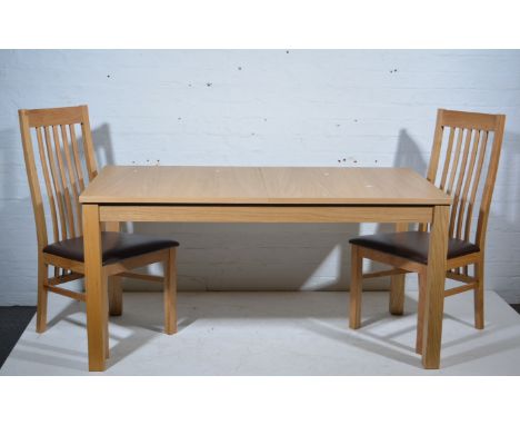 A modern laminated light wood extending dining table and eight chairs with vinyl seats.