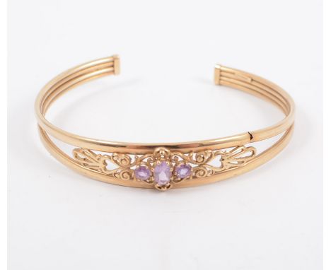 A 9 carat yellow gold amethyst set torque bangle, the three faceted stones set to the front of a two band open bangle, hallma