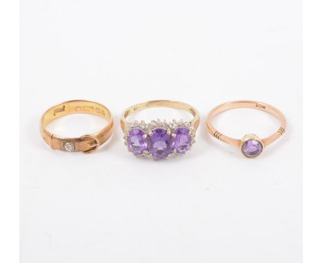 Two amethyst rings and a diamond buckle ring, a triple stone amethyst ring surrounded by twenty eight small diamonds in a 9 c