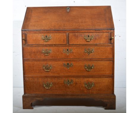 George III oak bureau, fall front enclosing an interior, well-fitted with drawers and pigeon holes, above two short and three