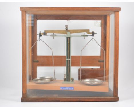 A set of laboratory balance scales in glazed cabinet with box of metric weights.