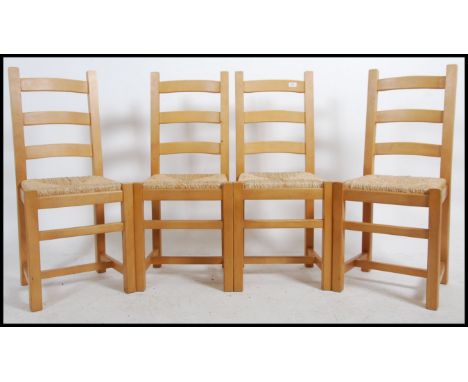 A set of four 20th century light oak ladder back dining chairs with rattan weave seats raised on square legs united by stretc
