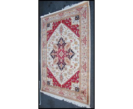 A large North Western Iranian / Persian Heriz carpet - rug having beige ground with geometric decoration and borders. Measure