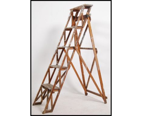 A vintage early to mid 20th century industrial wooden skeleton / trellis step ladder with cast iron brackets and makers marks