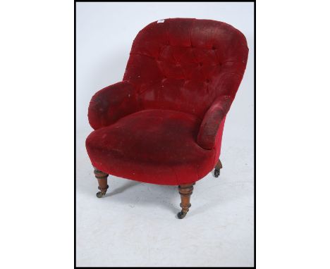 A Victorian 19th century mahogany tub armchair being raised on turned legs with button backed red velour upholstered seat