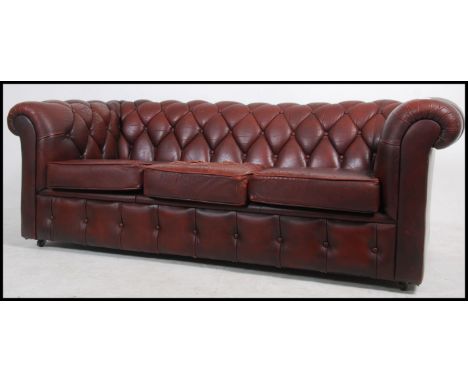 An antique style oxblood red leather Chesterfield sofa settee having buttoned back leather scrolled arms and back rests with 