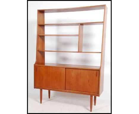 A 1970's Danish teak wood room divider bookcase being raised on tapered legs with tambour cupboard base having a series of mo