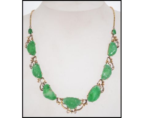 A vintage 14 ct gold and jade necklace with carved jade panels set within a foliate mount having a stylized hook clasp. Measu