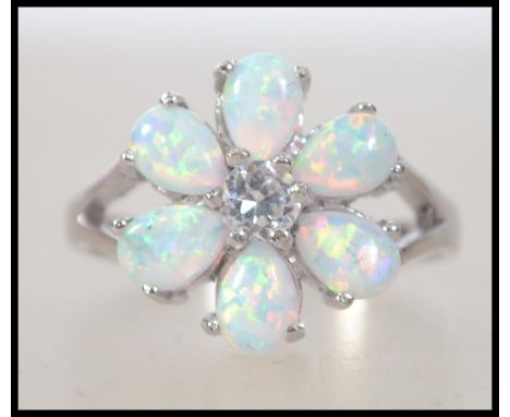 A ladies silver and opal flower head ring  having pierced shoulder to the shank. Total weight 3.9g / Size R.5