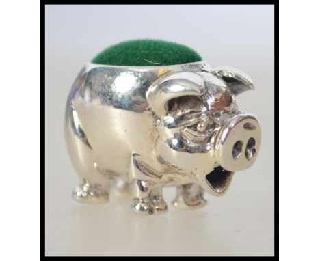 A pretty silver pin cushion in the form of a miniature pig having green baize cushion atop. Total weight 7.8g. 2cms long