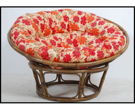 A retro 1970's bamboo pod chair having chintz upholstered large cushion on bamboo cage and base that adjusts - swivels move t