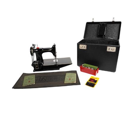 A Singer 221k electric sewing machine, with manual, mat, and accessories, contained in a carry case.