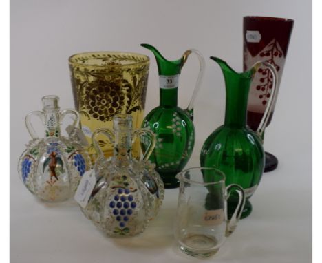 A pair of green glass ewers, with white enamel decoration, 23 cm high, a Mary Gregory style clear glass jug, 9.5 cm high, and
