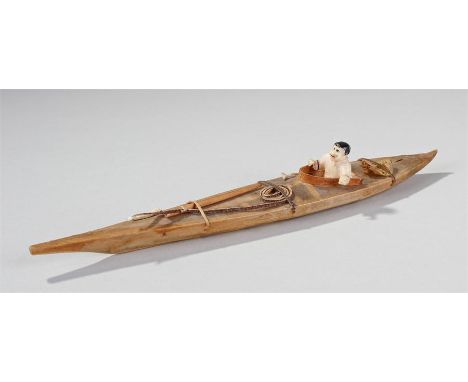 Inuit canoe, with a walrus ivory carved figure seated in a canoe with tied fishing equipment, 23cm long