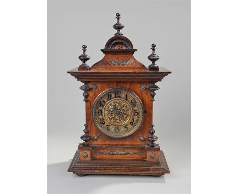 Early 20th Century German walnut mantel clock, the three finial top with arch above a gilt dial and Arabic hours, shaped base