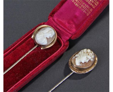 Two Victroian stick pins, the first of a classical man facing left, the second cased example with a hooded lady, (2)