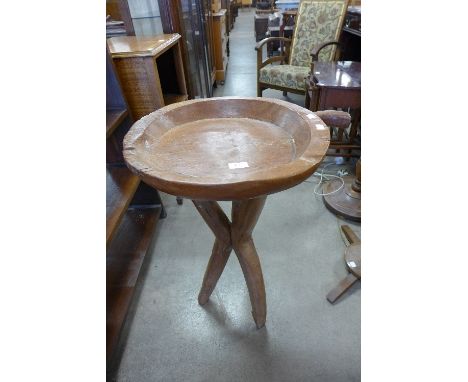 An ethnic carved wood tripod table