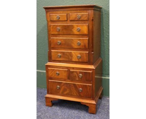 Flame cut mahogany multi drawer bedside chest raised on bracket supports, 77 cm high x 38 cm wide. 