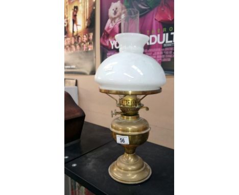 A brass oil lamp with opaque shade