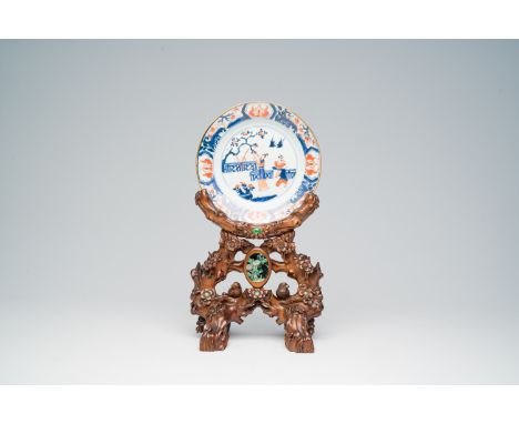 Full title: A Chinese Imari style plate with figures on a terrace on a carved rootwood pedestal with inlay, Kangxi and laterD