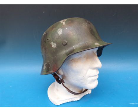 A German military helmet with camouflage finish, the leather liner marked possibly Guggenbergen