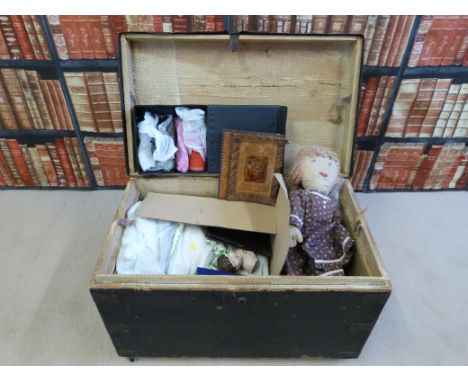 A vintage wooden metal-studded trunk containing a collection of textiles, dolls, leather Gladstone bag, gaiters etc