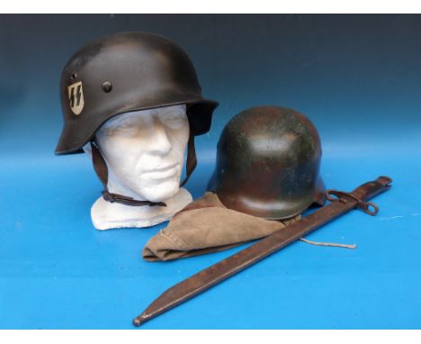 Two German helmets, one with SS and swastika emblems, together with a helmet cover with Nazi emblem 5-44 to inside and a WWI 