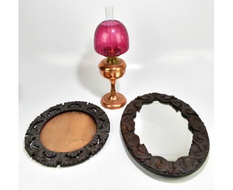 Two early 20th century oak carved wall mirrors,&nbsp;length of largest example 58cm, and a copper oil lamp with cranberry col