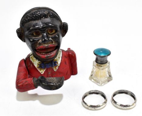 A cast iron 'Little Joe' novelty money box, height 13cm, two hallmarked silver napkin rings and a hallmarked silver and ename