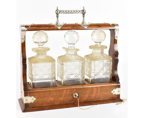 An oak three bottle tantalus with hallmarked silver mounts for James Dixon & Sons, Sheffield 1903, height 33cm, length 35cm.A