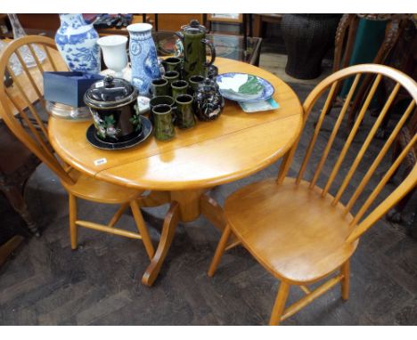 A circular beech drop leaf breakfast tables and a pair of matching stick back Windsor chairs 