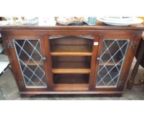 A low reproduction oak bookcase with glazed lead light doors and open centre panel 