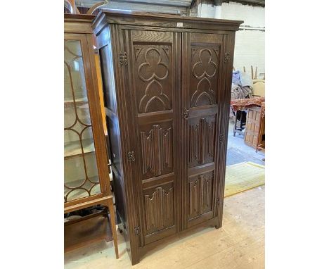 A 1920's Gothic revival wardrobe, the moulded top over two panel doors decorated with tray foils, linen folds and arches, int