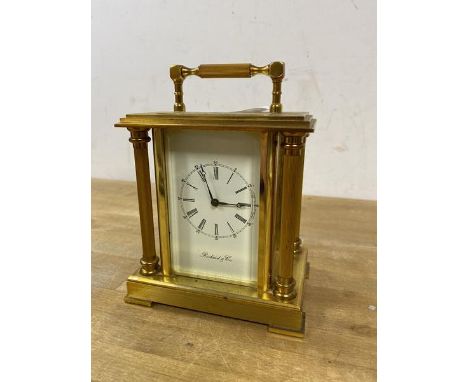 A Richard and Cie carriage style mantel clock with fixed handle over a dial with roman numerals with fluted columns to corner