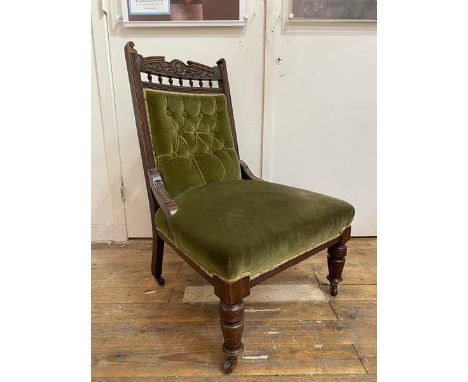 An Edwardian easy chair with carved crest rail with floral decoration between scrolled final's to supports over banister frie