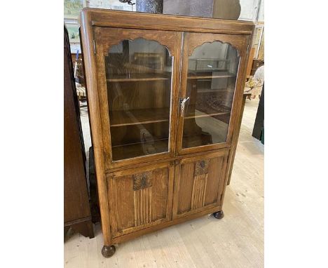 A 1930's / 40's oak bookcase over cabinet the caddy top over two glazed doors before two shelves over single cabinet having t