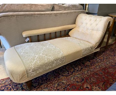 A late Victorian walnut framed chaise long, upholstered in floral damask, arm rest raised on spindle gallery, the frame carve