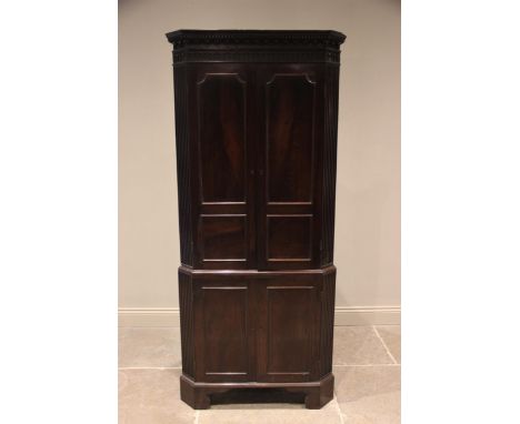 A George III mahogany freestanding corner cupboard, the moulded dentil cornice above a blind fretwork frieze and a pair of cu