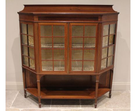 An Edwardian mahogany and satinwood crossbanded display cabinet, of angular bowfront form, with a galleried back and reeded e