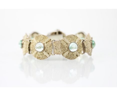 An early 20th century silver gilt bracelet by Theodore Fahrner, designed as seven circular panels set with blue-green pastes 