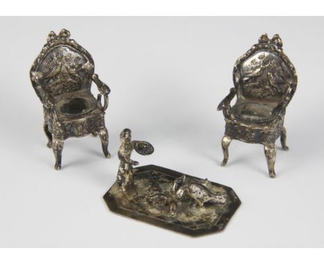 A pair of silver coloured miniature fauteuil chairs, the padded seats upon cabriole legs and scrolling open arms, the shaped 