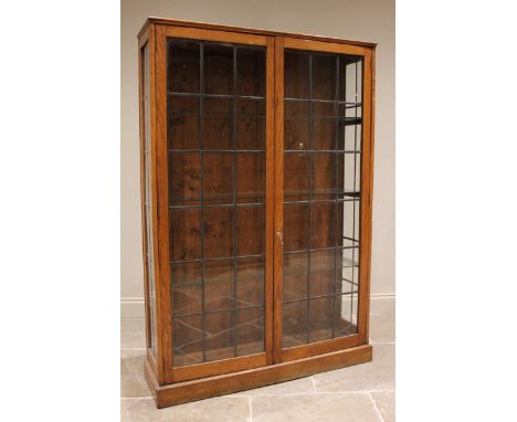 An early 20th century oak and leaded glass vintage school trophy cabinet, the twin doors opening to three later glass shelves