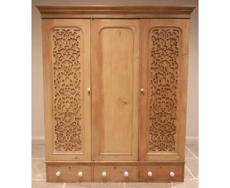 A Victorian pine triple wardrobe, the moulded cornice above three doors, the plain panelled centre door flanked by doors appl