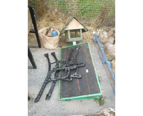 A pair of cast iron bench ends, part of a bird table, shelf and a bucket of odds including air operated oil gun.