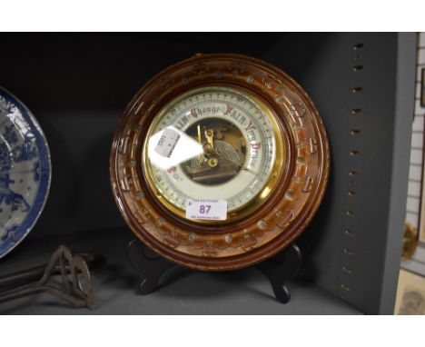 An aneroid barometer of button design with carved mahogany frame having enamel face dial
