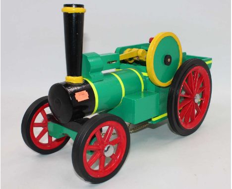 A wooden home made model of a Burrell type traction engine, finished in two tone green with red spoked wheels and rubber tyre